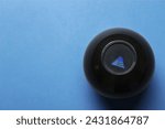Small photo of Magic eight ball with prediction Answer Unclear Ask Later on blue background, top view. Space for text