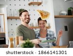 Young couple making pancakes at  home. Loving couple having fun while cooking.