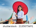 Small photo of A young Burmese woman Standing and holding red umbrella on U-bein bridge, Mandalay, Myanmar. Space for text.