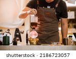 Professional coffee maker - Barista using coffee siphon brewing hot espresso at coffee shop brewing syphon alternative method. Startup Business Concept.