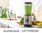 Blender with healthy smoothie and ingredients on table in kitchen