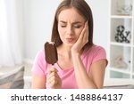 Young woman with sensitive teeth and cold ice-cream at home