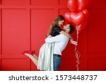 Happy young couple with heart-shaped balloons on color background. Valentine's Day celebration