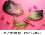 Female wigs, brush, comb and curlers on color background