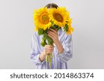 Woman with beautiful sunflowers on light background
