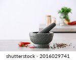 Mortar with spices and pestle on light table in kitchen