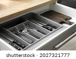 Drawer with set of knives and boards in kitchen