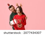 Young woman receiving Christmas gift from her boyfriend on color background