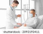 Small photo of Doctor and mature man undergoing course of chemotherapy in clinic