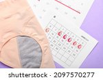 Period panties and menstrual calendar on color background, closeup