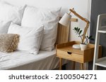 Wooden bedside table with lamp and flowerpot in light room