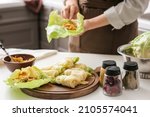 Small photo of Woman preparing stuffed cabbage rolls on table in kitchen, closeup