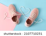 Pair of sportive shoes and heart made of laces on color background