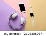 Modern headphones, smart watch and mobile phone on color background