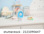Modern baby monitor, toys and teether on table in room