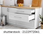 Stylish counters with opened drawers in light kitchen