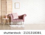 Stylish sofa, vase with flowers and folding screen near white brick wall