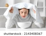 Small photo of Young woman doing steam inhalation at home to soothe and open nasal passages
