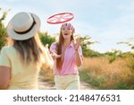 Small photo of Happy young women playing frisbee on summer day