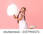 Cute little girl with cotton candy on pink background