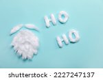 Santa beard made of cotton wool and words HO HO on blue background