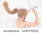 Blonde woman with ponytail lying on soft bed