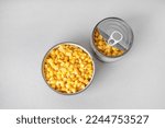 Bowl and tin can with canned corn on grey background
