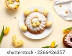 Composition with tasty Easter cake, painted eggs and tulip flowers on color background