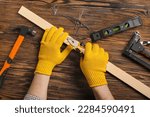 Man with pliers pulling out nail from wooden plank on table