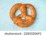 Tasty pretzel with poppy seeds on color background