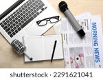 Small photo of Laptop with eyeglasses, microphones, notebook and newspapers on light wooden background