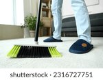Small photo of Young man sweeping carpet with broom at home, closeup