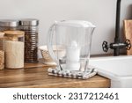 Water filter jug with napkin on kitchen counter near light wall