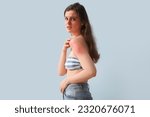 Small photo of Allergic young woman with sunburned skin on blue background