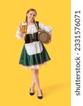 Beautiful Octoberfest waitress with beer and barrel on yellow background