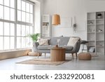 Small photo of Interior of light living room with grey sofa, wooden coffee table and big window