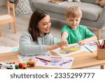 Small photo of Nanny with little boy drawing at home