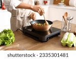 Young Asian man frying vegetables in kitchen, closeup