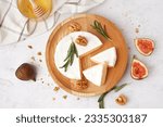 Plate with pieces of tasty Camembert cheese on light background