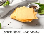 Small photo of Slices of tasty processed cheese on white tile background