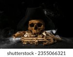 Small photo of Travel equipment with golden nuggets, human skull, old manuscripts and pirate hat on black background