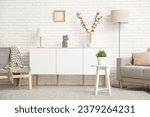 Interior of light living room with grey sofa, armchair and white sideboard