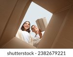 Happy young couple with open moving box, view from inside