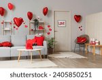 Interior of festive living room with grey sofa, heart-shaped balloons and glasses of wine on coffee table. Valentine's Day celebration