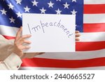 Small photo of Woman holding IMPEACHMENT picket poster against USA flag background