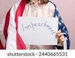Small photo of Woman with USA flag holding IMPEACHMENT picket sign on pink background