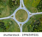 Top down aerial drone view of a small traffic roundabout on a quiet road