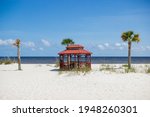 Beautiful summer landscape by the ocean with white sand and clear blue skies, palm trees and a gazebo on a summer sunny day.Ken Combs Pier, Gulfport, Mississippi, USA - 7-4-2019