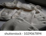 Small photo of A small print of the baby's hand and legs on polymeric material next to children's lacy clothing