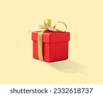 Red present box with gold ribbon on a yellow background. Gift concept for a birthday, wedding or new year. Copy space.